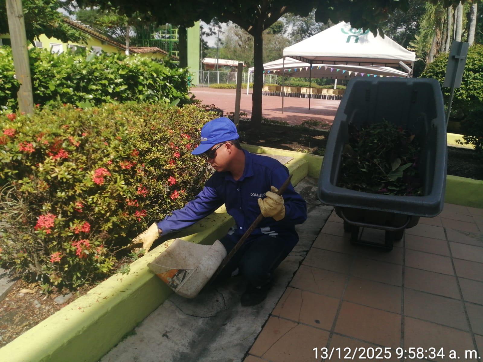 Operario Don Aseo podando jardín con flores en instalaciones del cliente